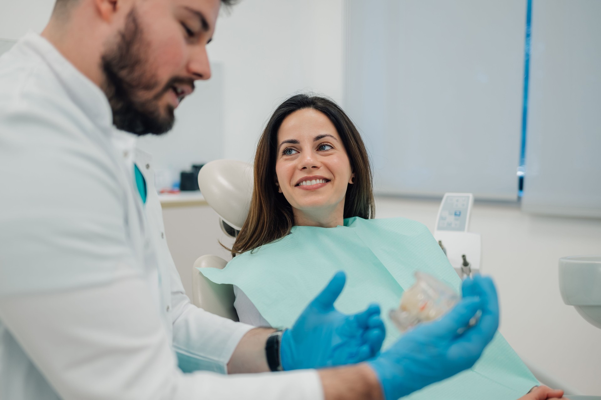 Dentist showing dentures to patient in dental clinic