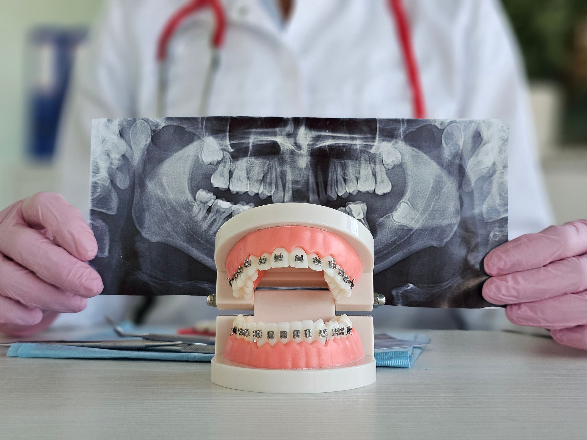 Ortodoncista que examina el modelo de ortodoncia junto con radiografías dentales en el concepto de entorno clínico